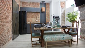A dining area with a brick wall, a wooden table with chairs, and a bench.