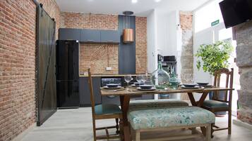 A dining area with a brick wall, a wooden table with chairs, and a bench.