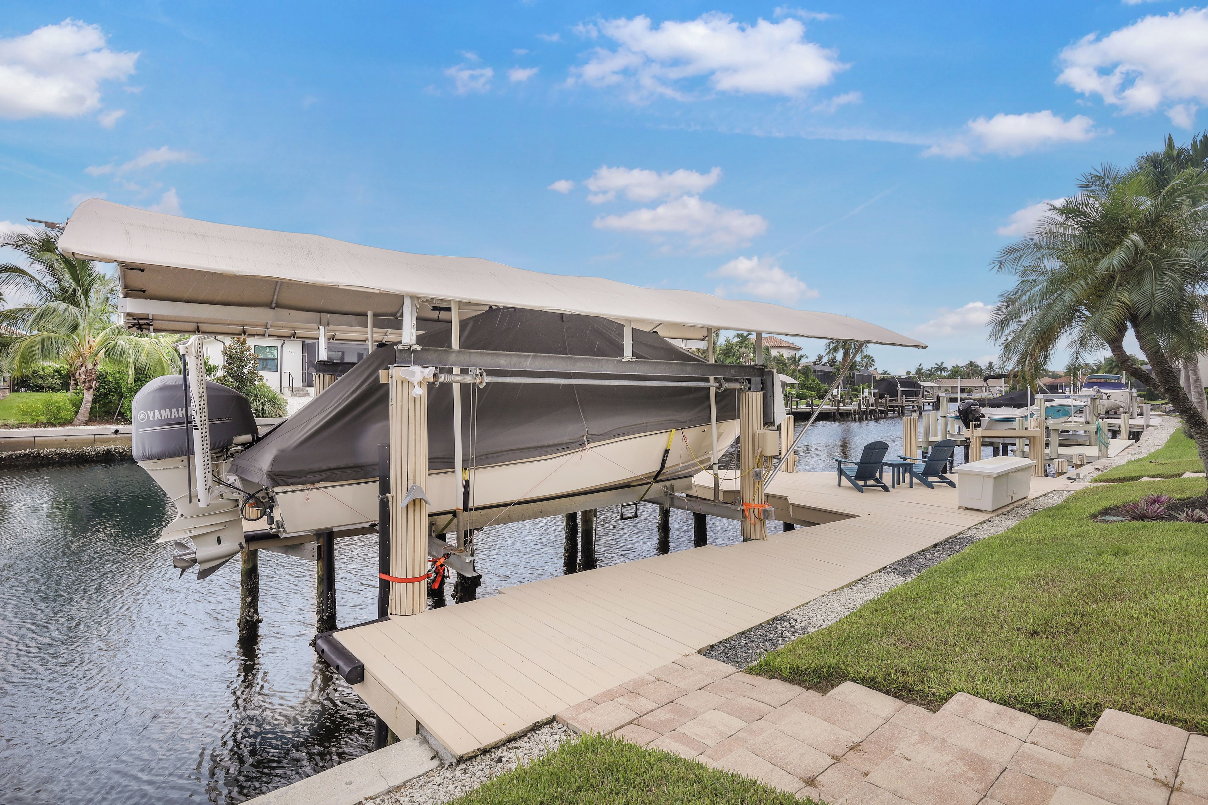 A boat docked at a marina with a covered deck, a Yamaha outboard motor, and a lounge area with chairs and tables.