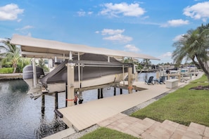 A boat docked at a marina with a covered deck, a Yamaha outboard motor, and a lounge area with chairs and tables. - Alluring Waterfront Home | W Exposure, Pool/Dock (Marco Island)