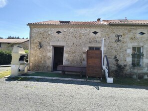 A stone building with a tiled roof, a wooden door, and a small window. - A vacation rental on a beautiful, charming property, ideal for exploring the Médoc region. (Vendays-Montalivet)
