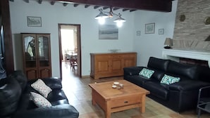 Una sala de estar con un sofá de cuero negro, una mesa de centro de madera y una chimenea.