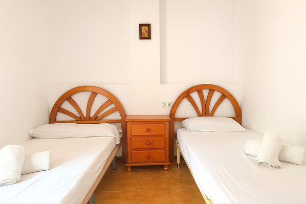 A room with two wooden beds, a nightstand, and a small wall-mounted picture.