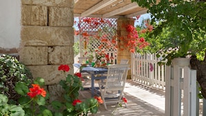 An outdoor patio with a table and chairs, surrounded by a white picket fence and flowering plants. - 3025 Villa Verdeoasi by Barbarhouse (Lecce)
