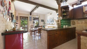 A kitchen with wooden cabinets, a red countertop, and a dining area with chairs and a table. - 3025 Villa Verdeoasi by Barbarhouse (Lecce)