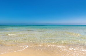 Een strand met helder ondiep water en een zandkust.