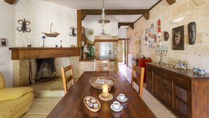 A rustic dining room with a wooden table, chairs, a fireplace, and a stone wall. - 3025 Villa Verdeoasi by Barbarhouse (Lecce)