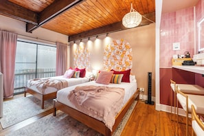 A bedroom with two beds, a wooden ceiling, a large window with curtains, and a pink wall. - Lincoln Park 3BR Townhome • Rooftop • King Suite • Sleeps 10 (Chicago)