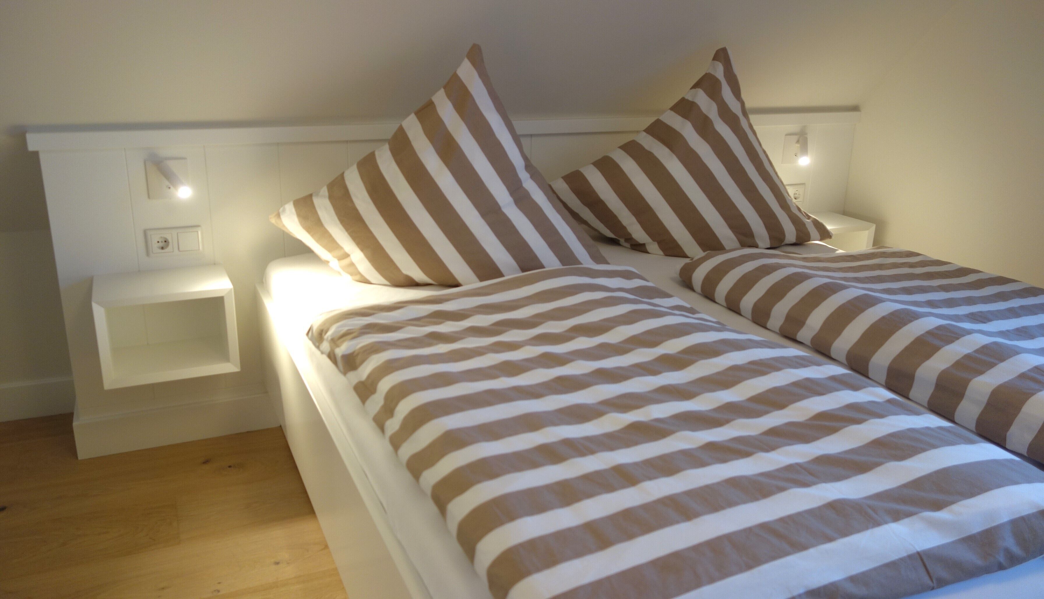 A bedroom with a bed, two nightstands, and a wall socket.
