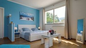Ein Schlafzimmer mit Bett, Nachttischen, einem Fenster und Blick ins Freie.