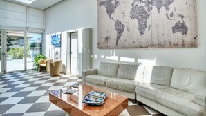 Eine moderne Lobby mit Schachbrettboden, einer großen Weltkarte an der Wand, einer Couch und einem Couchtisch mit Zeitschriften.