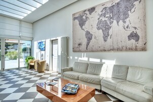 Un vestíbulo moderno con piso a cuadros, un gran mapa mundial en la pared, un sofá y una mesa de centro con revistas.