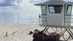 Ein Rettungsturm am Strand bei blauem Himmel und ruhiger See.
