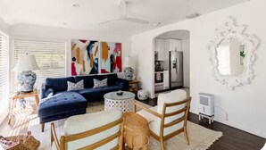 Ein modernes Wohnzimmer mit einem blauen Sofa, einem runden Couchtisch und einem weißen Sessel.