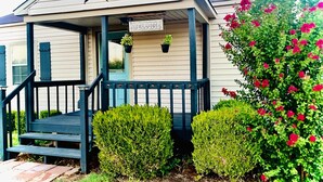 A building with a star on the roof, a 'WELCOME' sign, and potted plants on the porch.