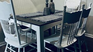 A dining area with a table and chairs, a textured rug, and a hanging light fixture.