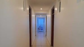 A long, narrow hallway with tiled flooring and white walls.