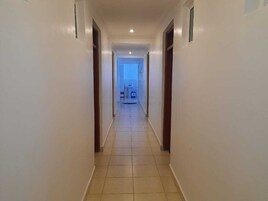 A long, narrow hallway with tiled flooring and white walls.