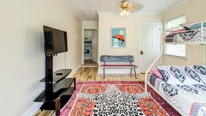 A bedroom with a TV, bunk beds, a bench, a patterned rug, and a ceiling fan. - Pools Paradise: 4  BR, 2  BA House in Wilmington, Sleeps 8 (Wilmington)