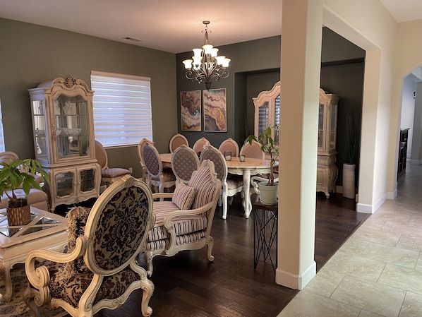 Uma sala de jantar com mobiliário requintado, um candelabro e obras de arte nas paredes.