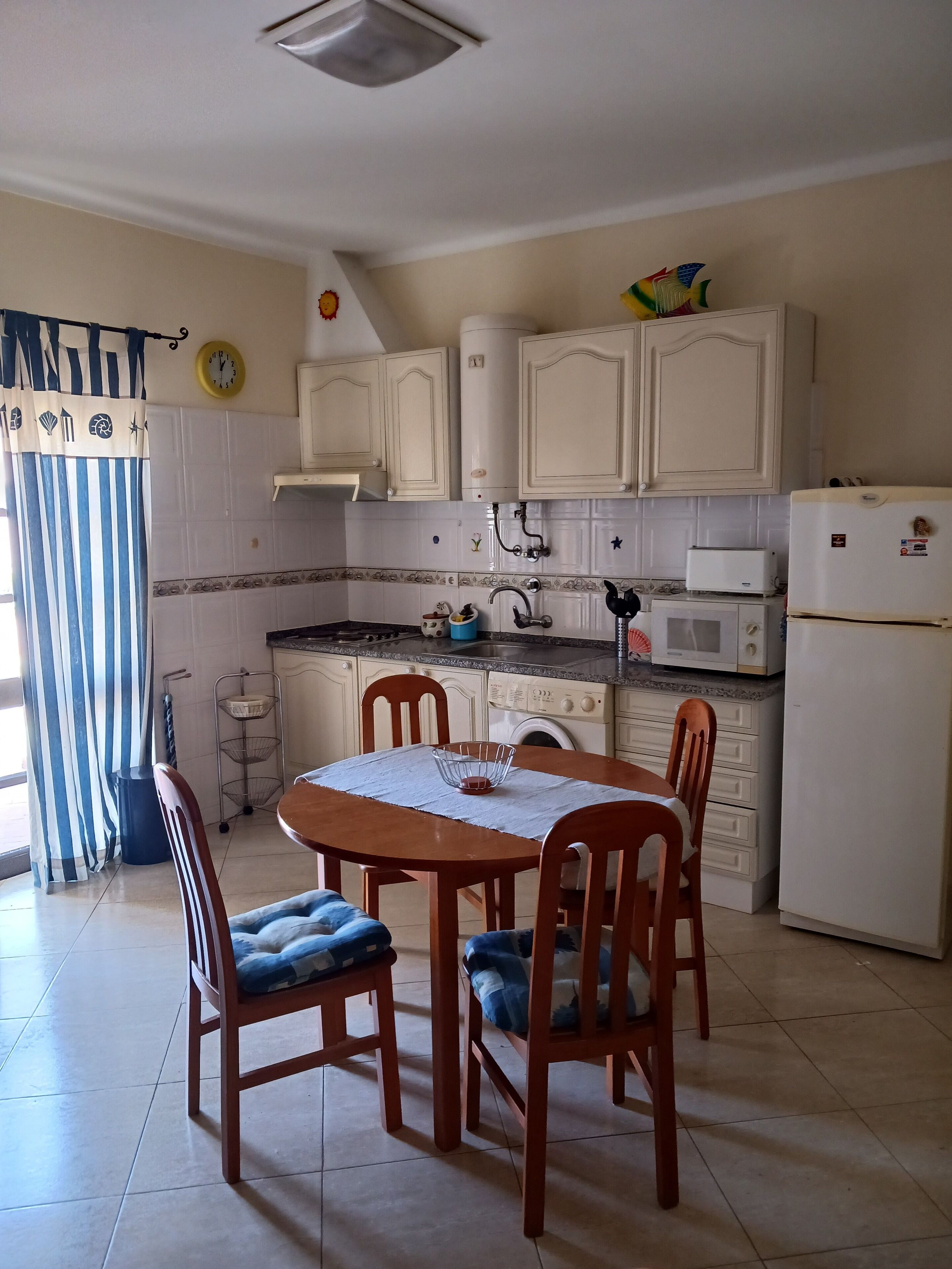 A kitchen with white cabinets, a microwave, a refrigerator, and a dining table with chairs.