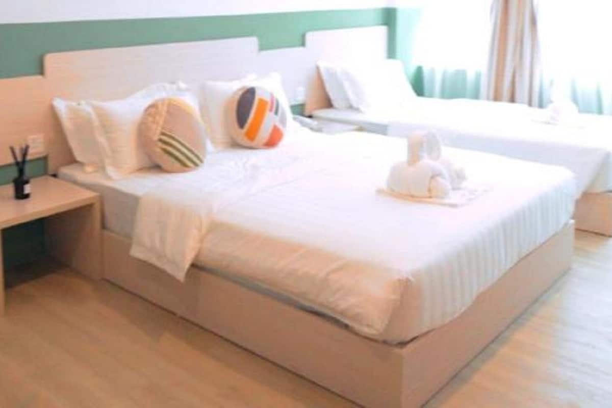 A hotel room with a bed, a nightstand, and a bedside table.