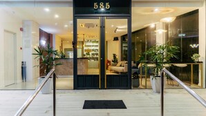 A hotel entrance with a number '585' above the doors, a reception desk inside, and potted plants outside. - All Are Welcome Lawas Boutique Hotel (Lawas)
