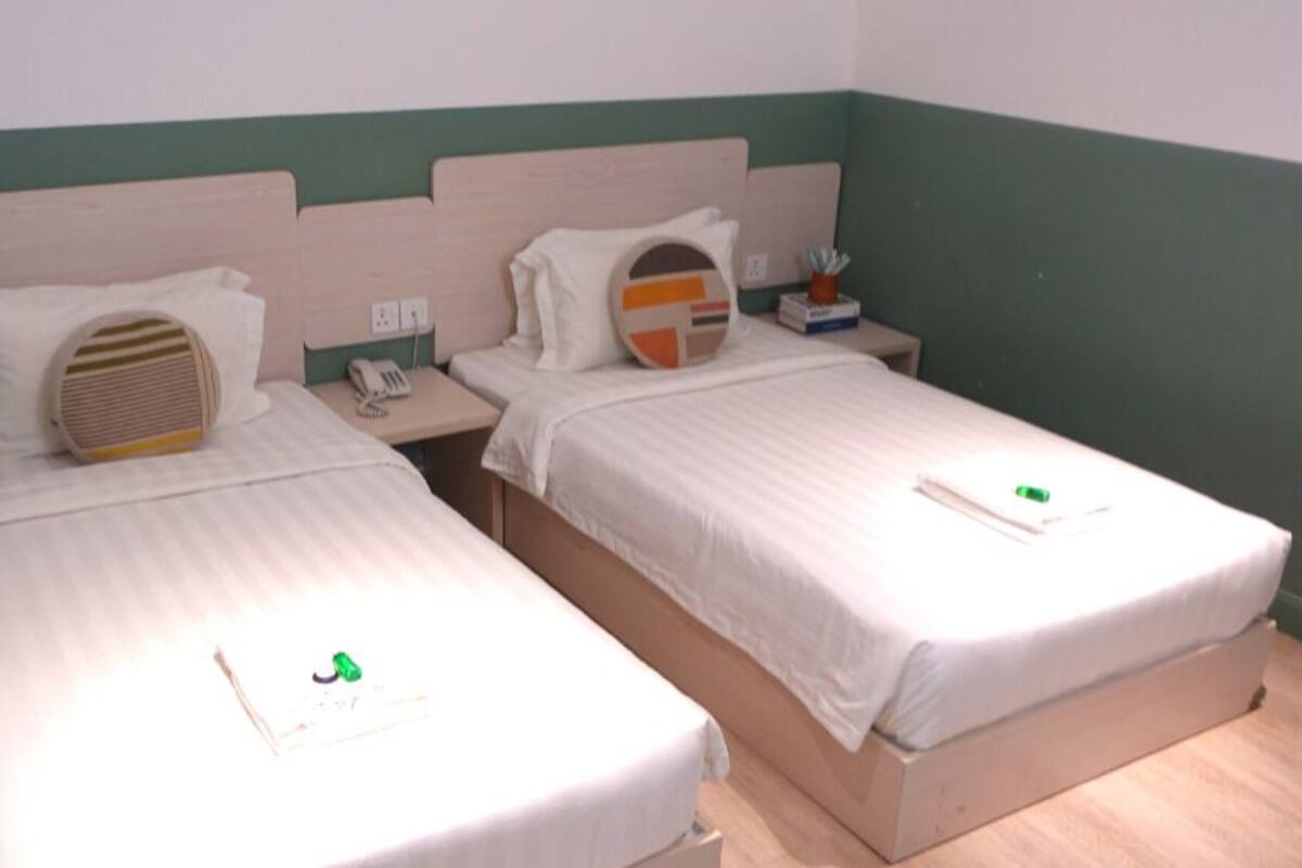Two single beds with headboards, a bedside table with a phone, and a wall socket.