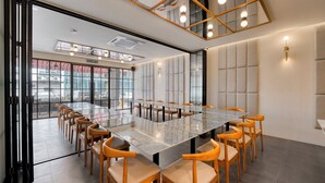 A conference room with a large marble table, wooden chairs, and a view of a building outside. - All Are Welcome Lawas Boutique Hotel (Lawas)