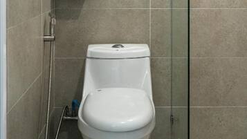 A modern bathroom with a white toilet, a glass shower enclosure, and a towel rack with a white towel.