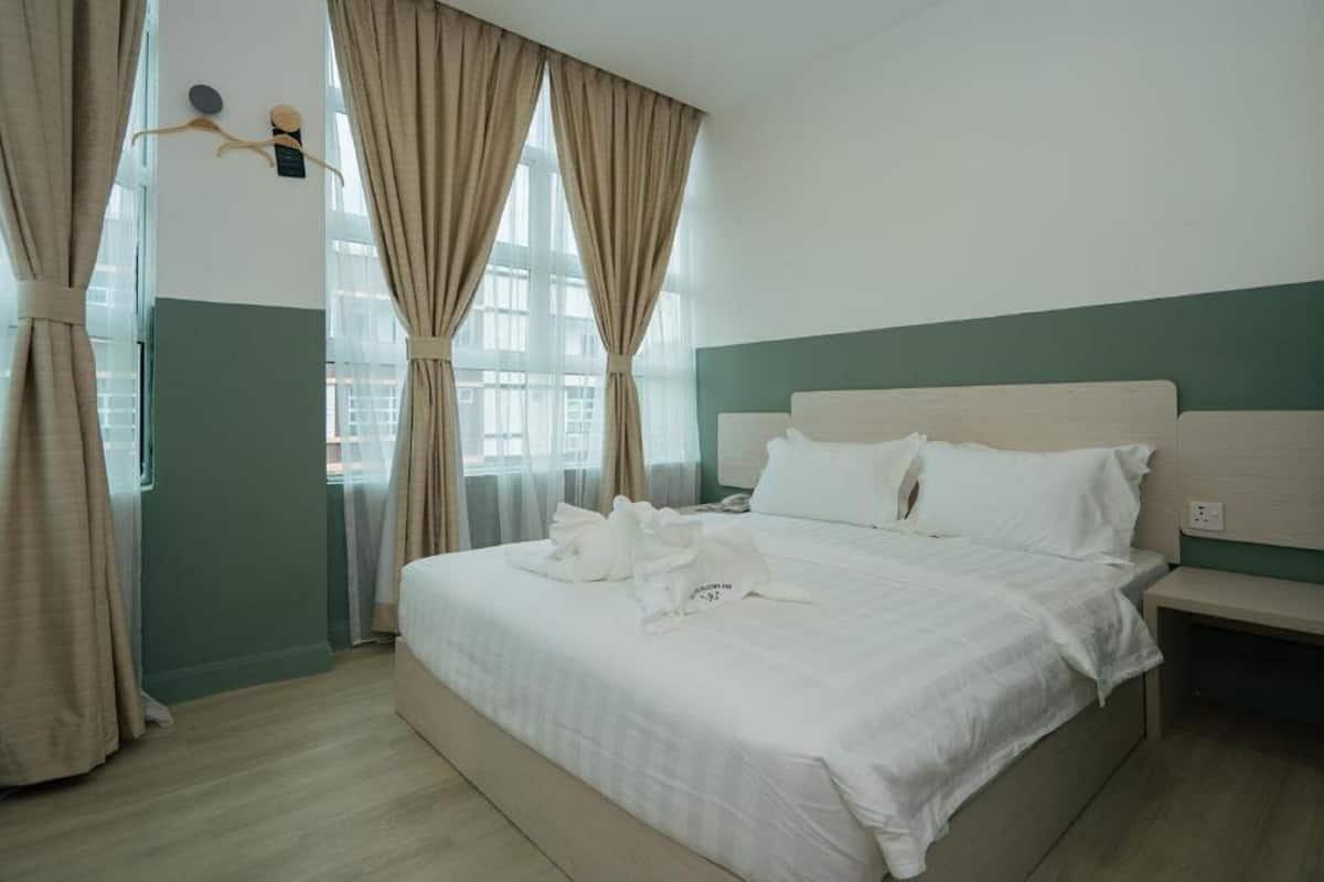 A hotel room with a bed, a bedside table, and curtains.