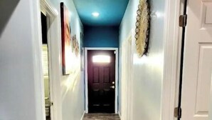 Un corridoio con pavimento in legno, pareti bianche e soffitto azzurro.