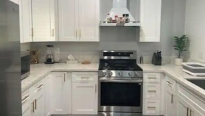 Una cucina moderna con mobili bianchi, un piano cottura in acciaio inossidabile e un forno integrato.
