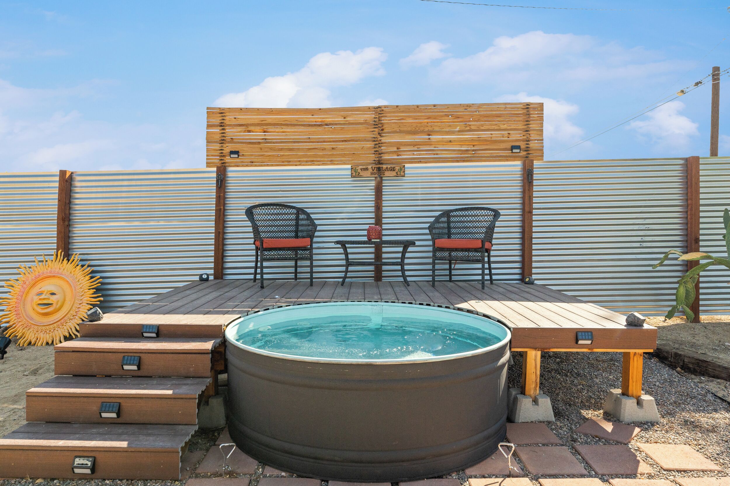 Un bain à remous avec des marches en bois, deux chaises et une pergola en bois.