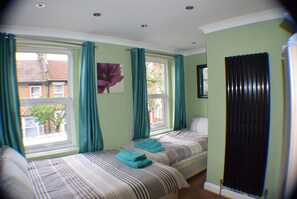 Two single beds with striped bedding, a window with curtains, and a radiator.
