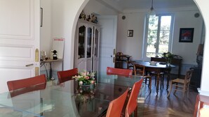 Zona de menjador amb taula de vidre, cadires vermelles i un centre de taula amb flors.