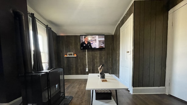 Ein Wohnzimmer mit Kamin, einem flachbildfernseher an der Wand, einem Tisch mit einer Dekoration und einer Couch.
