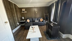 Ein Wohnzimmer mit einem dunkelgrauen Sofa, einem weißen Couchtisch, einer TV-Konsole und einem Kamin.