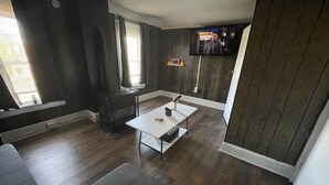 Ein Wohnzimmer mit Kamin, Wandfernseher und einer Couch.