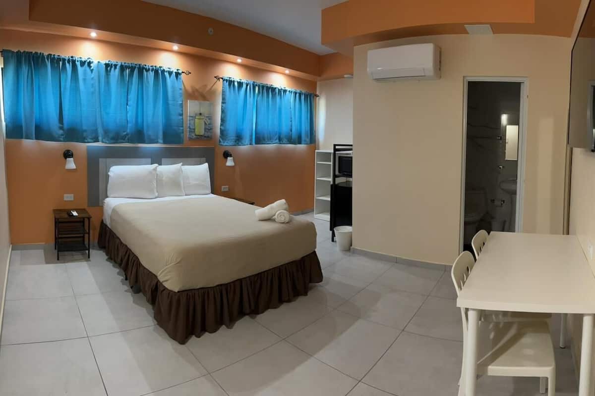 Ein Hotelzimmer mit Bett, Schreibtisch und Fernseher.