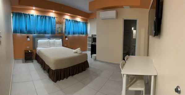 Une chambre d’hôtel avec un lit, un bureau et une télévision.