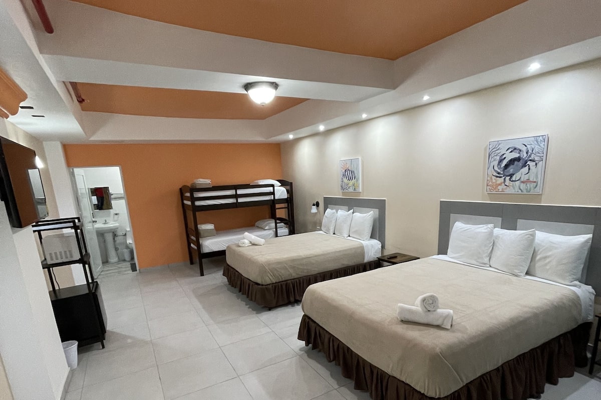 Ein Hotelzimmer mit zwei Betten, einem Badezimmer und einem kleinen Schreibtisch.