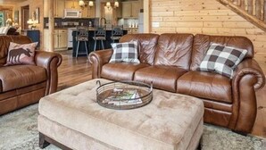 A spacious living room with a leather sofa set, a coffee table, and a wooden staircase.