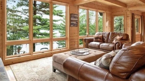 A spacious cabin with large windows offering views of trees and a clear sky.