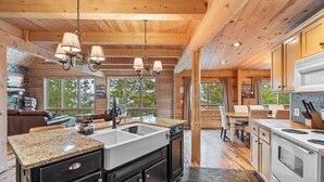A spacious kitchen with granite countertops, a large sink, and stainless steel appliances. There is a dining area with a table and chairs, and a cozy seating area with a fireplace.