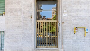 A building entrance with a metal gate, a window with a view of the street, and a sign on the wall. - Few steps from Vatican City - 2 double rooms (Roma)