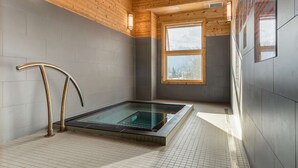 A modern spa room with a glass-enclosed hot tub, wooden ceiling, and large windows. - Heart of Canmore - Pet Friendly with Shared Rooftop Hot Tub (Canmore)