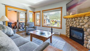 A spacious living room with a stone fireplace, large windows, and a cozy seating area. - Heart of Canmore - Pet Friendly with Shared Rooftop Hot Tub (Canmore)