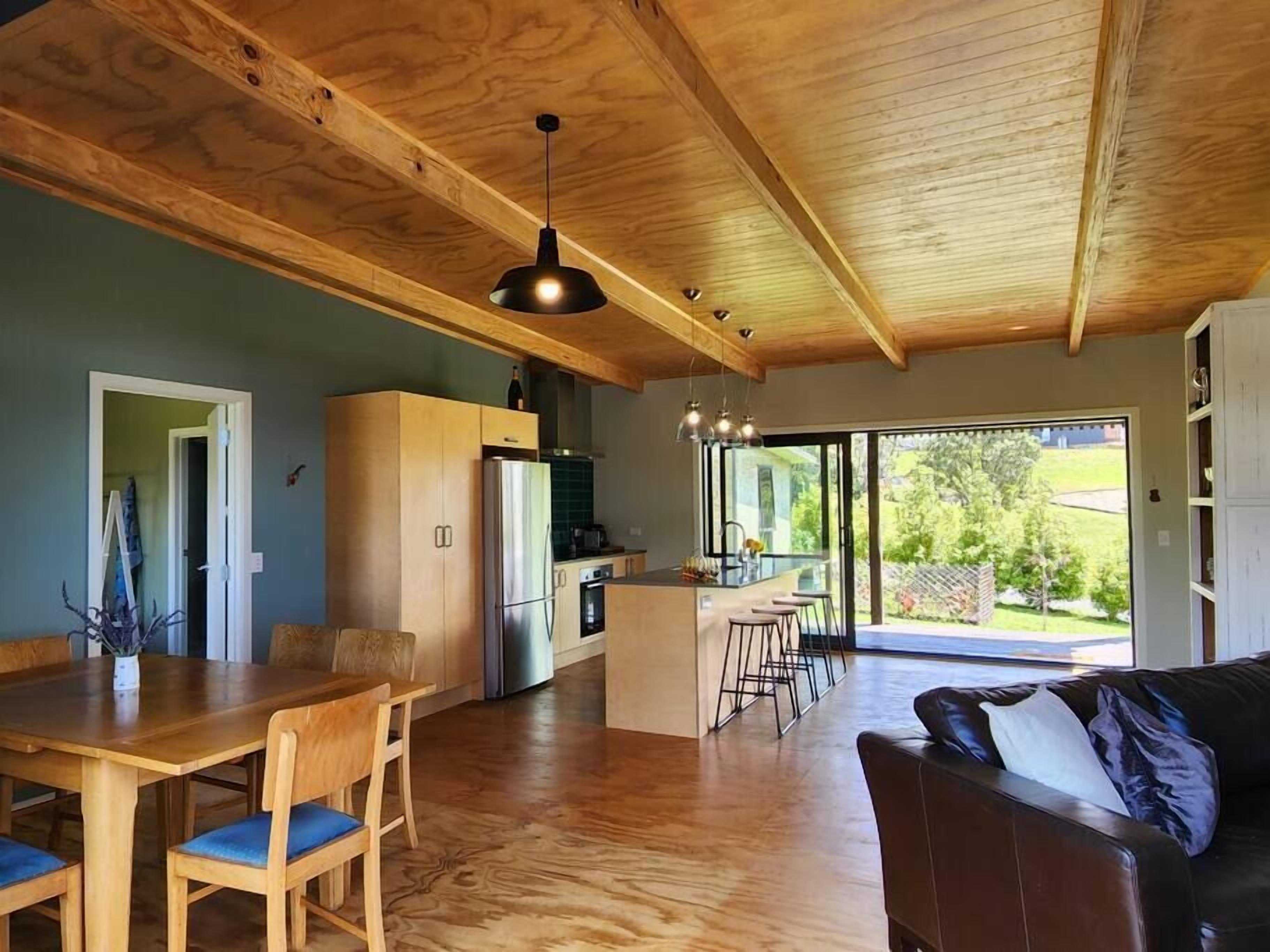 Una cocina amplia con armarios de madera, un refrigerador de acero inoxidable y un comedor con mesa y sillas de madera.