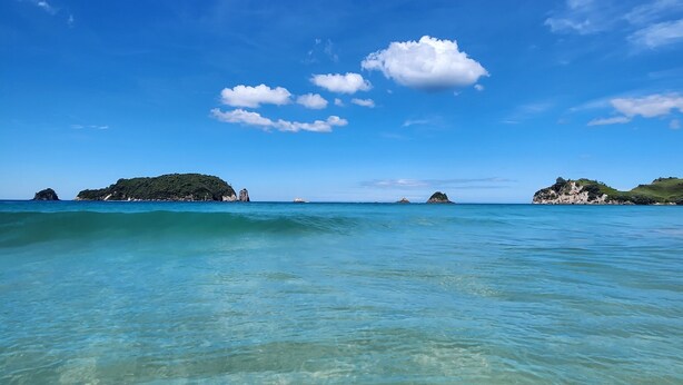 A clear view of a coastal landscape with calm waters and distant islands under a blue sky. - Hahei Hideout Retreat - private and surrounded by bush. Pond and small orchard (Hahei)